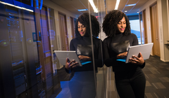 Woman on laptop leaning on servers