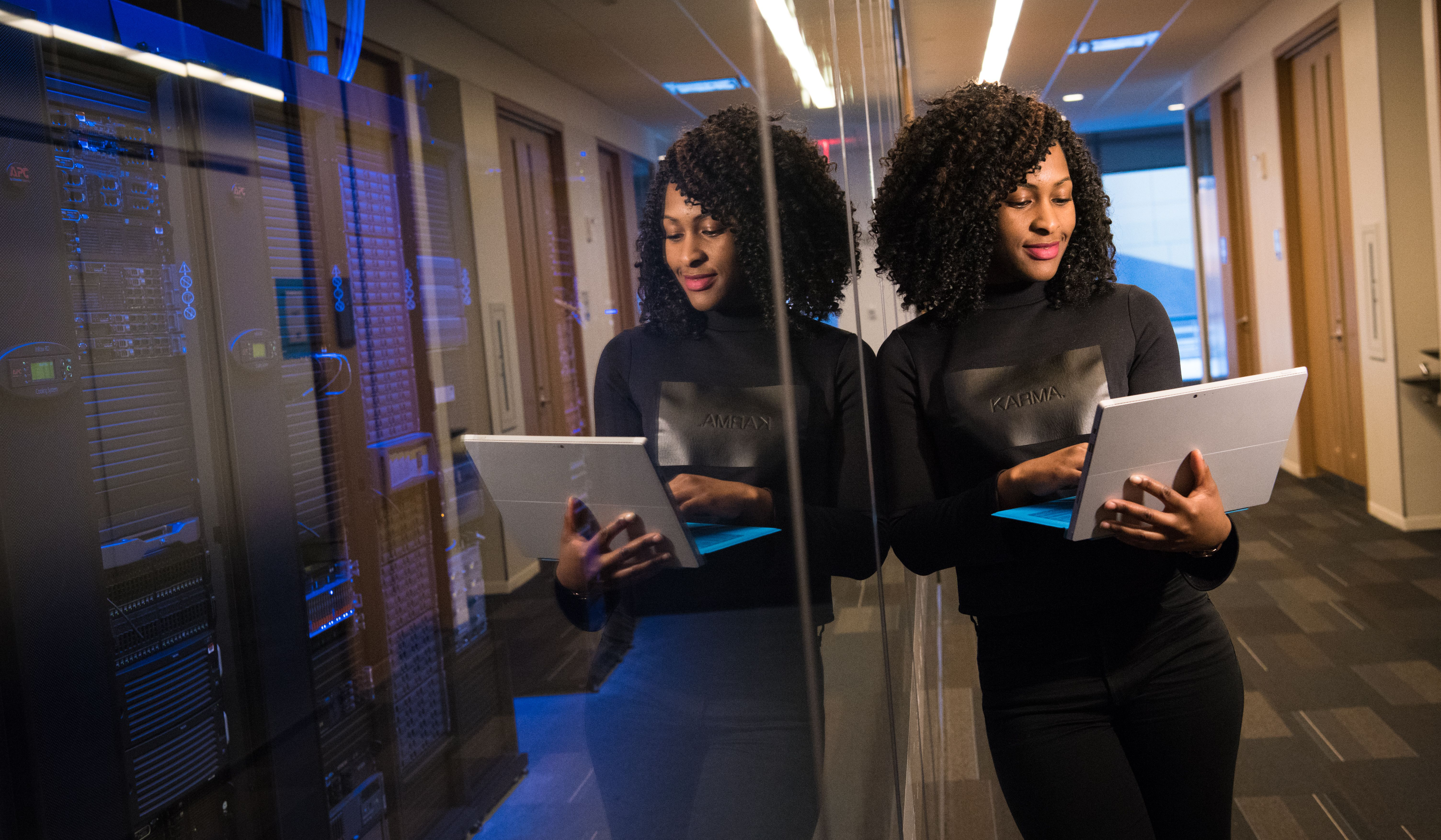 Woman on laptop leaning on servers