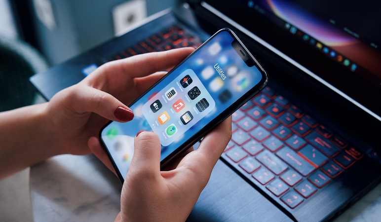 Person holding a phone above a laptop