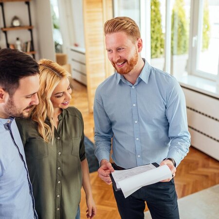 Contractor talks through project plan with couple in their sunny living room