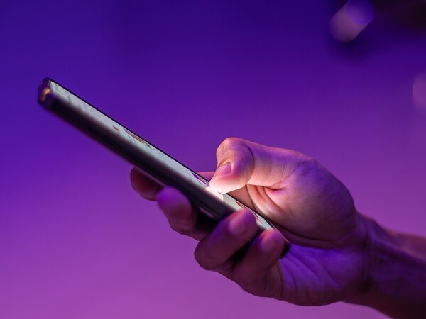 Hand holding and interacting with a smartphone against a purple background