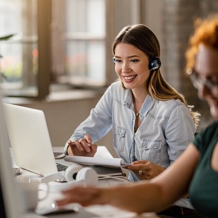 Customer service professional using headset while working on laptop in modern office