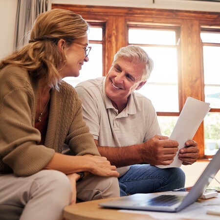 Laptop, senior couple and retirement planning with documents while sitting on sofa in the living room