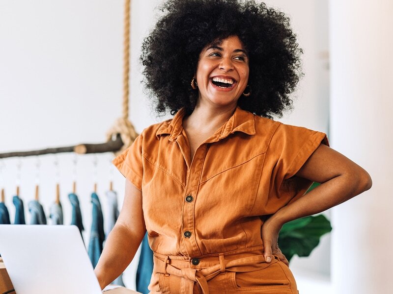 Owner of a clothing retail store smiling and talking with a customer in her shop